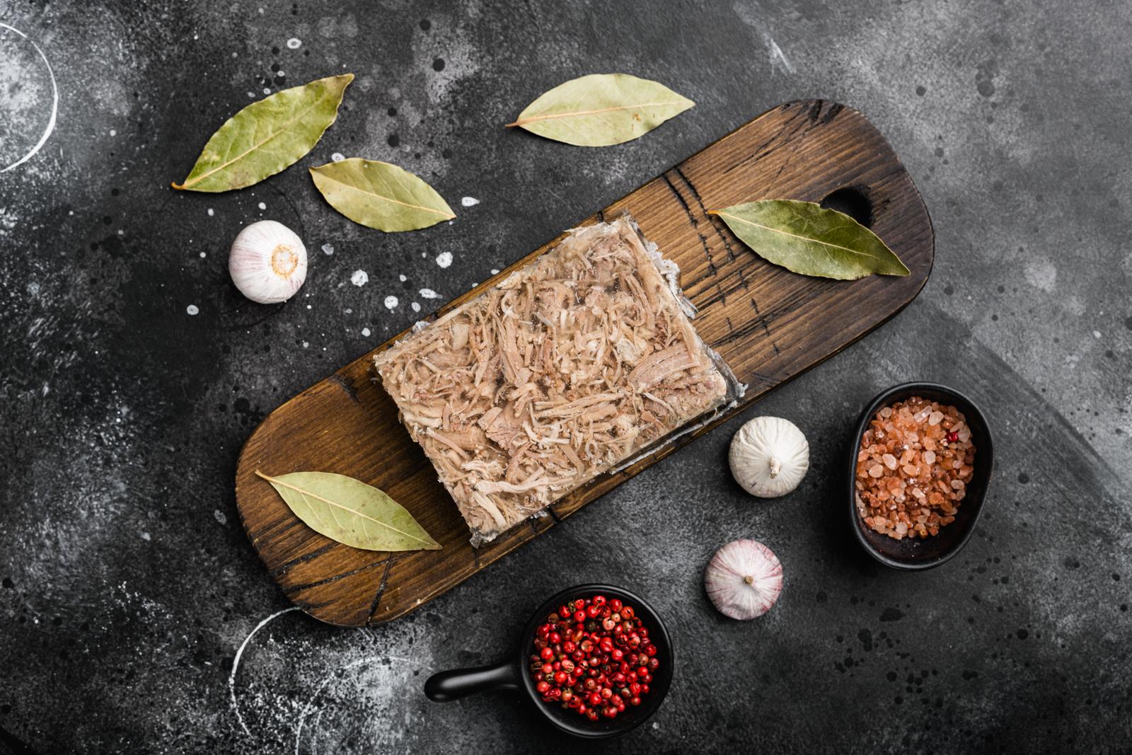 Jellied meat, beef aspic, traditional Russian dish, on black dark stone table background, top view flat lay